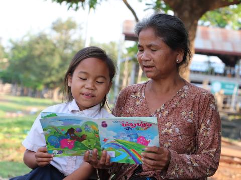 Kam and her grandmother as she reads her storybook.