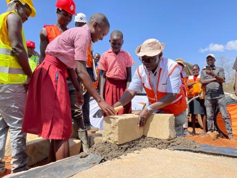 World Vision Kenya National Director and a pupil lay the foundation for the construction of a secondary school in Aroket