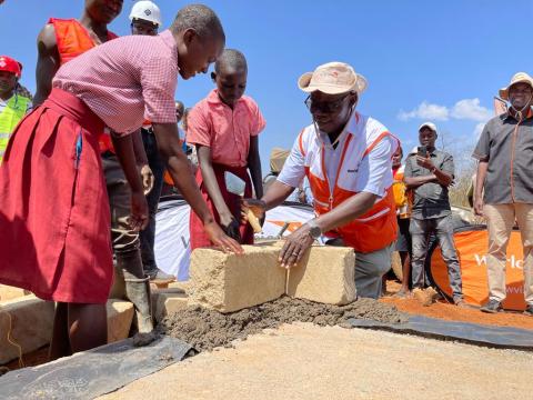 World Vision Kenya National Director and a pupil lay the foundation for the construction of a secondary school in Aroket