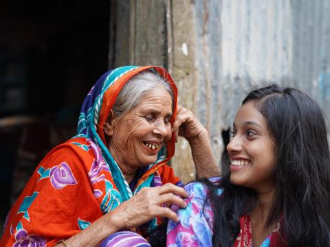 Two figures, an old woman and a young girl, smiling