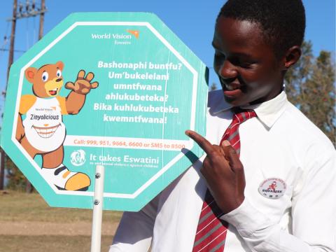 A child posing with a placard which calls for people to report sexual abuse against children in Eswatini