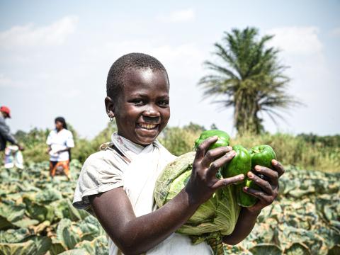 A girl holding cabbages and green pepper