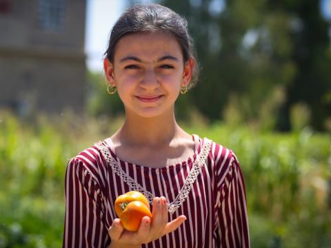 A little girl holding a tomato