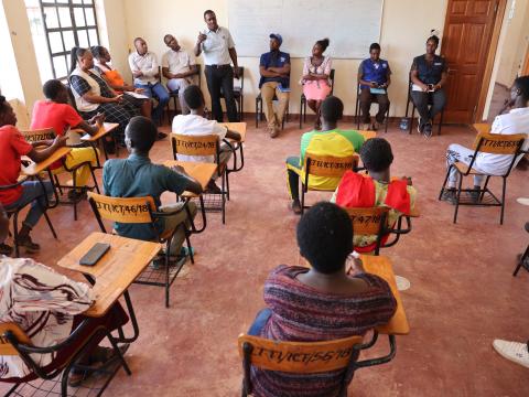 The Laisamis Technical Training Institute Principal Mr. Rotich (standing) addressing the IOM Kenya, World Vision Kenya, Candle of Hope Foundation, and youth sponsored by the JTIP Project during a visit to the institution. 