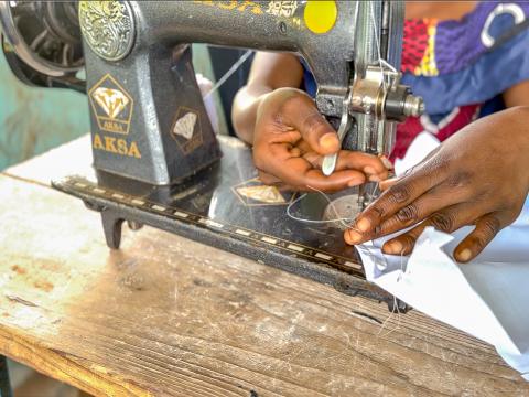 Les mains d'une de jeunes filles appuyées par le projet entrain de coudre