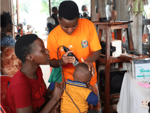 Women shaving a child's head