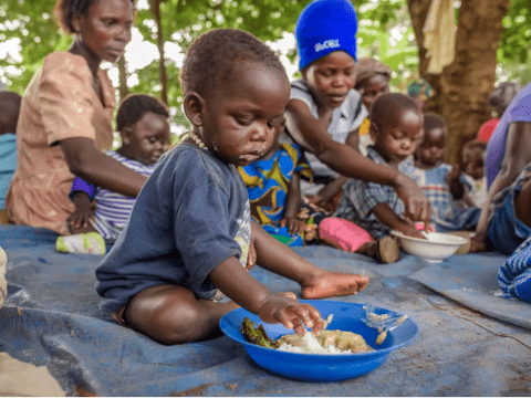 Little boy eating out of a blue bowl