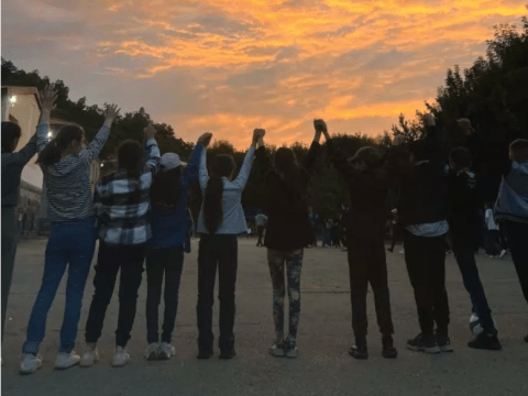 Children holding hands reaching to sky