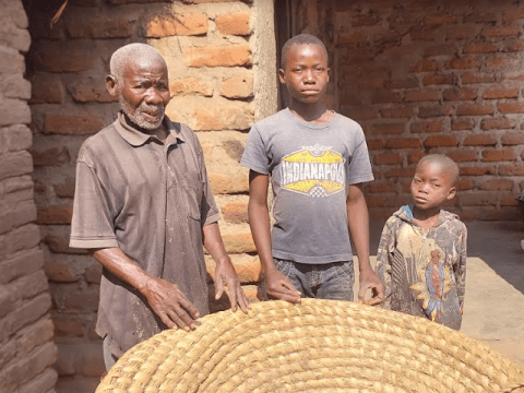 A man and his two sons standing in front of their empty barn