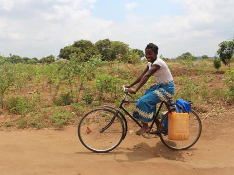 A portrait of a girl who relies on her bicycle to cover the long distances needed to fetch water, but with the borehole now near her home, everything is much easier.