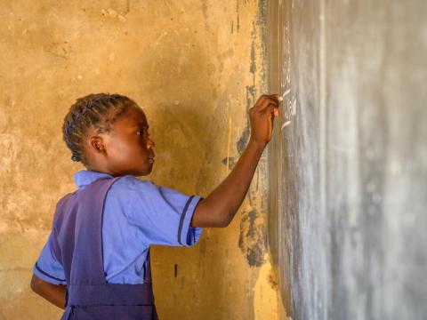 girl writes on a chalkboard