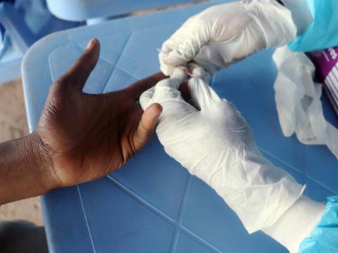 A gloved hand taking blood from an ungloved hand