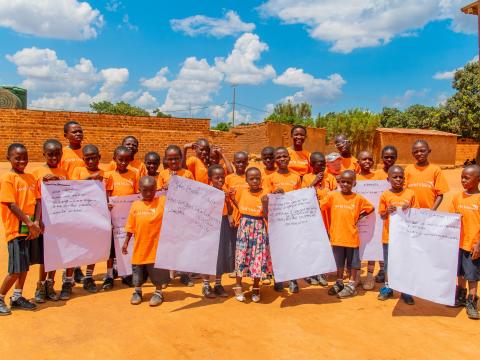 Alicia and children posing and showing messages at the World Children's Day celebration