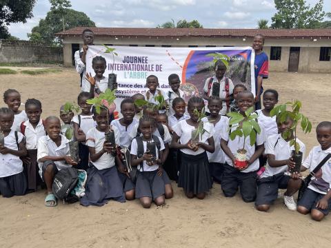 Des enfants tenant des arbres avant de les planter 