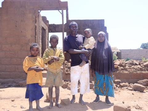 Marcelino and his children standing in front of the destroyed house