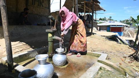 Woman standing at water spigot in Myanmar