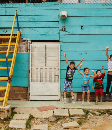 Children jumping upfront of blue wall