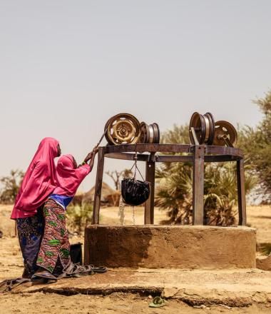 woman and her daughter dressed in pink draw water from a well