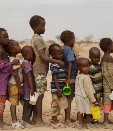 On 4 August 2023 in Turkana, Kenya, 4-year-old Sunday (blue stripes) stands next to his 9-year-old brother Blue and a group of children.